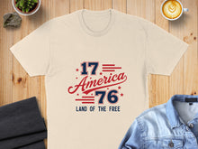 Load image into Gallery viewer, Cream t-shirt with "1776 America Land of the Free" in red and blue text.
