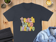 Load image into Gallery viewer, Dark t-shirt with "Teach Love Inspire" text in colorful retro lettering.
