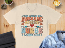 Load image into Gallery viewer, Cream t-shirt with "This is what an awesome hospice nurse looks like" text.
