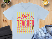 Load image into Gallery viewer, Light blue t-shirt with "TEACHER" and motivational text about tough days.
