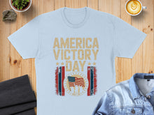Load image into Gallery viewer, Light blue t-shirt with "AMERICA VICTORY DAY MAY 08" and US flag graphic.
