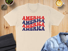 Load image into Gallery viewer, Cream t-shirt with "AMERICA AMERICA AMERICA" text in red and blue.
