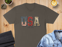Load image into Gallery viewer, Brown t-shirt with distressed "USA EST. 1776" graphic featuring American flag and cityscape.

