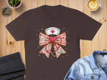 Load image into Gallery viewer, Brown t-shirt with a pink bow graphic featuring a nurse's hat, stethoscope, and hearts.
