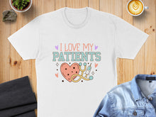 Load image into Gallery viewer, White t-shirt with "I love my patients" text and medical icons.

