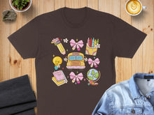 Load image into Gallery viewer, Brown t-shirt with colorful school-themed doodles and a pink school bus.
