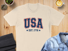 Load image into Gallery viewer, Cream t-shirt with "USA EST. 1776" in red and blue text.
