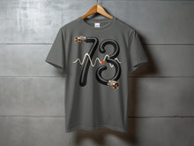 Load image into Gallery viewer, Grey t-shirt with black "73" graphic made of cable and connectors.
