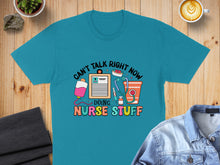 Load image into Gallery viewer, Teal t-shirt with "Can't Talk Right Now Doing Nurse Stuff" graphic.
