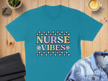 Load image into Gallery viewer, Teal t-shirt with "Nurse Vibes" text in colorful retro font and checkered pattern.
