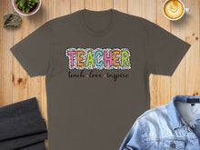 Load image into Gallery viewer, Brown t-shirt with "TEACHER" in colorful speckled letters and "teach love inspire" below.
