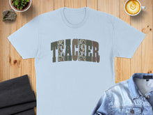 Load image into Gallery viewer, Light blue t-shirt with "TEACHER" in a camouflage pattern.
