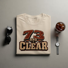 Load image into Gallery viewer, Cream t-shirt with distressed "73 AND CLEAR" text and microphone graphic.
