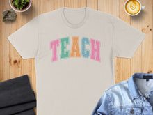 Load image into Gallery viewer, Cream t-shirt with "TEACH" in colorful block letters.
