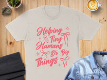 Load image into Gallery viewer, Beige t-shirt with pink text "Helping Tiny Humans Do Big Things".
