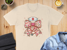 Load image into Gallery viewer, Beige t-shirt with nurse cap, stethoscope, and XOXO heart graphic.
