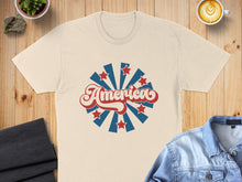 Load image into Gallery viewer, Cream t-shirt with "America" in red script surrounded by blue stars and rays.

