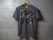 Load image into Gallery viewer, Dark grey t-shirt with black number 73 formed from a textured hose with connectors.
