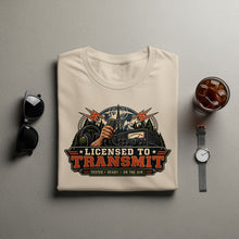 Load image into Gallery viewer, Cream t-shirt with "Licensed to Transmit" graphic featuring radio equipment and a hand holding a microphone.
