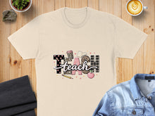 Load image into Gallery viewer, Beige t-shirt with "TEACH" in leopard print and plaid, featuring apple and book graphics.
