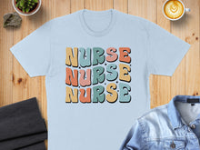 Load image into Gallery viewer, Light blue t-shirt with stacked "Nurse" text in retro colors.
