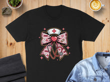 Load image into Gallery viewer, Black t-shirt with a pink ribbon, stethoscope, and medical symbols design.
