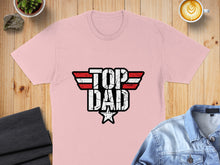 Load image into Gallery viewer, Pink t-shirt with distressed "TOP DAD" logo, on a wooden surface.
