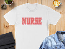 Load image into Gallery viewer, White t-shirt with "NURSE" in pink text, displayed with casual items.
