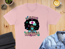 Load image into Gallery viewer, Pink t-shirt with a graphic of a nurse with butterflies and the text "NURSING is a work of Heart".
