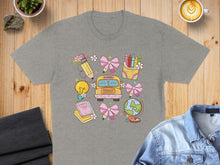 Load image into Gallery viewer, School-themed graphic with bus, lightbulb, books, crayons, globe, and bows on t-shirt.
