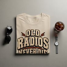 Load image into Gallery viewer, Light cream t-shirt with distressed "Old Radios Never Die" text and lightning bolts.
