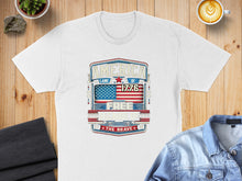 Load image into Gallery viewer, White t-shirt with "AMERICA LAND OF THE FREE 1776 BECAUSE THE BRAVE" graphic.
