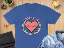 Load image into Gallery viewer, Blue t-shirt with "Nursing is a work of heart" text and a heart monitor line.

