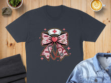 Load image into Gallery viewer, Dark t-shirt with a pink bow featuring stethoscope, crosses, and medical symbols.
