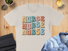 Load image into Gallery viewer, Beige t-shirt with "NURSE" repeated in colorful retro font.
