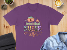 Load image into Gallery viewer, Purple t-shirt with "Livin' That Nurse Life" text and heart graphic.
