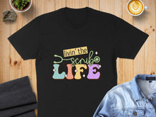 Load image into Gallery viewer, Black t-shirt with colorful "Livin' the Scrube LIFE" text and stethoscope.
