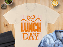 Load image into Gallery viewer, Peach t-shirt with orange "Lunch Day" text and pink stripes.

