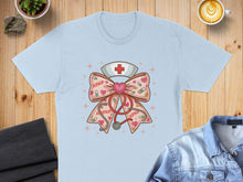 Load image into Gallery viewer, Light blue t-shirt featuring a nurse-themed bow with stethoscope, heart, and XOXO pattern.
