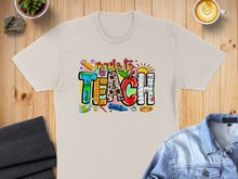 Load image into Gallery viewer, T-shirt graphic with "Made to Teach" text, school supplies, and apple.
