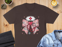Load image into Gallery viewer, Brown t-shirt with a pink bow featuring a nurse's cap, stethoscope, and XOXO hearts.

