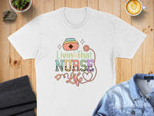 Load image into Gallery viewer, White t-shirt with "Livin' That Nurse Life" text and stethoscope.
