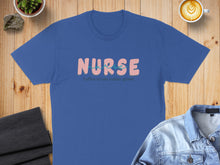Load image into Gallery viewer, Blue t-shirt with "Nurse" text in pink and teal, surrounded by "coffee, scrubs, rubber, gloves".
