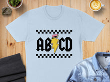 Load image into Gallery viewer, Light blue t-shirt featuring black "ABCD" text with a yellow lightning bolt.
