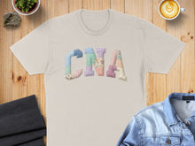 Load image into Gallery viewer, Cream t-shirt with "CNA" spelled out in colorful patchwork fabric letters.
