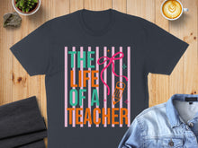 Load image into Gallery viewer, T-shirt with "The Life of a Teacher" text and pink ribbon.
