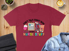 Load image into Gallery viewer, Burgundy t-shirt with "Can't talk right now, doing nurse stuff" text and medical graphics.

