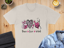 Load image into Gallery viewer, Peace love scrub text with stethoscope, heart, and syringe on a beige t-shirt.
