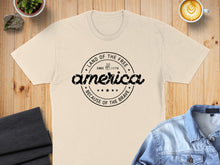 Load image into Gallery viewer, Cream t-shirt with "Land of the Free" graphic and "Since 1776 Because of the Brave".
