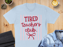 Load image into Gallery viewer, Light blue t-shirt with "Tired Teachers Club" text and a red bow graphic.
